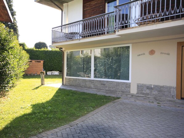 Ein zweistöckiges Gebäude mit Balkon, großen Fenstern und einem Steinfundament.