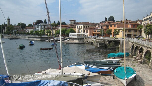 A marina with boats docked, a stone bridge, and buildings in the background. - Belvilla by OYO Michael's House (Lesa)