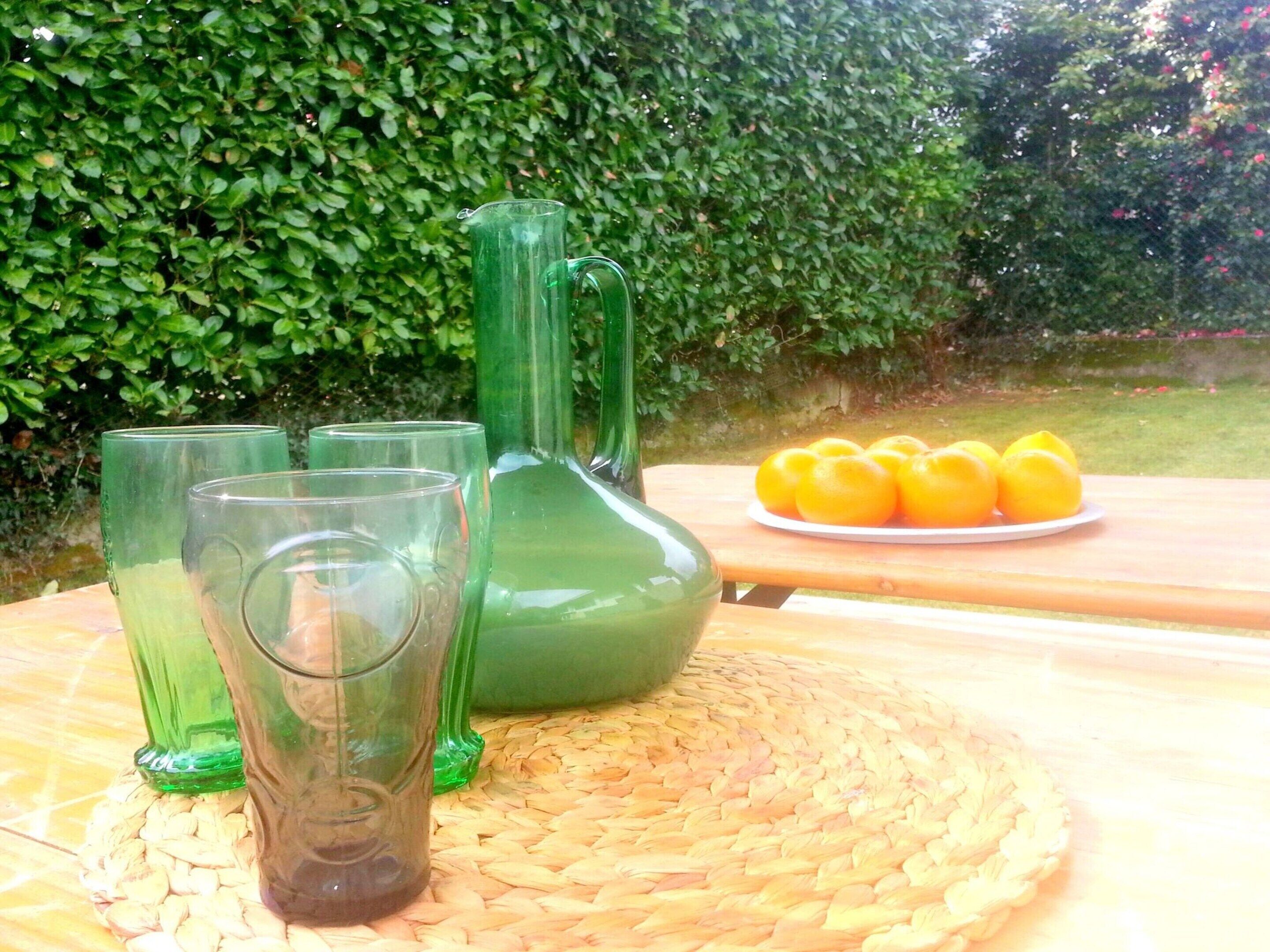 A table with green glassware and a woven placemat.