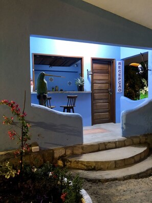 Un área de recepción con una puerta de madera, un letrero que dice "RECEPCAO" y una escultura de un pájaro.