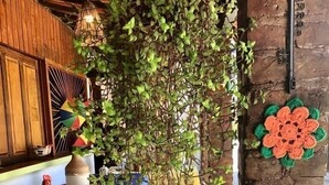 A rustic outdoor seating area with a stone floor, wooden beams, and a table covered with a blue tablecloth. - Pousada das Oliveiras (Ipojuca)