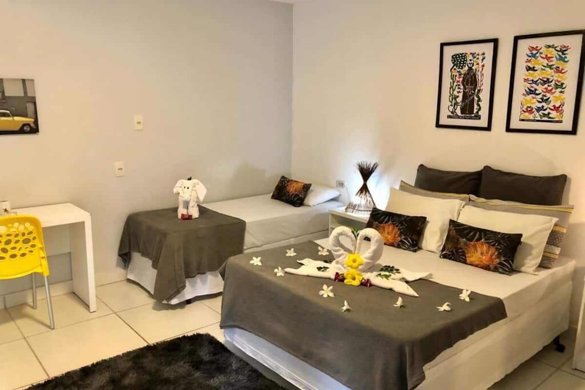 Quarto de hotel com duas camas, uma escrivaninha, uma cadeira e obras de arte nas paredes.