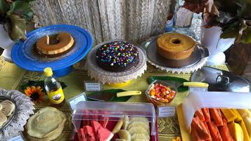 Una mesa con diversos postres y frutas, incluyendo pasteles, un pastel de chocolate con chispas de colores y una ensalada de frutas.