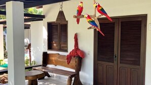 A covered outdoor seating area with a bench and a hanging bird feeder. - Pousada das Oliveiras (Ipojuca)
