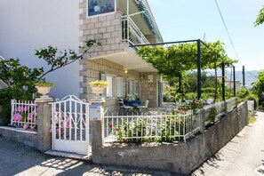 A residential property with a gated entrance, a covered porch, and a view of the surrounding greenery.