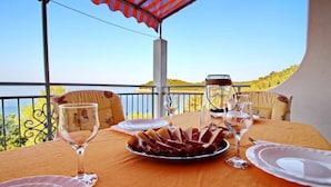 Une table dressée pour le dîner, avec vue sur la mer, des places assises en plein air et un ciel dégagé.