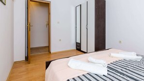 Um quarto com cama, porta de madeira, guarda-roupa e espelho.