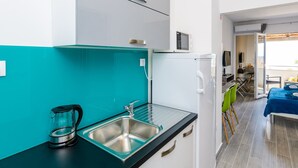 Una cocina moderna con un lavamanos, hervidor y microondas.