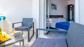 Un balcón con una mesa, sillas y una cama con colcha azul.