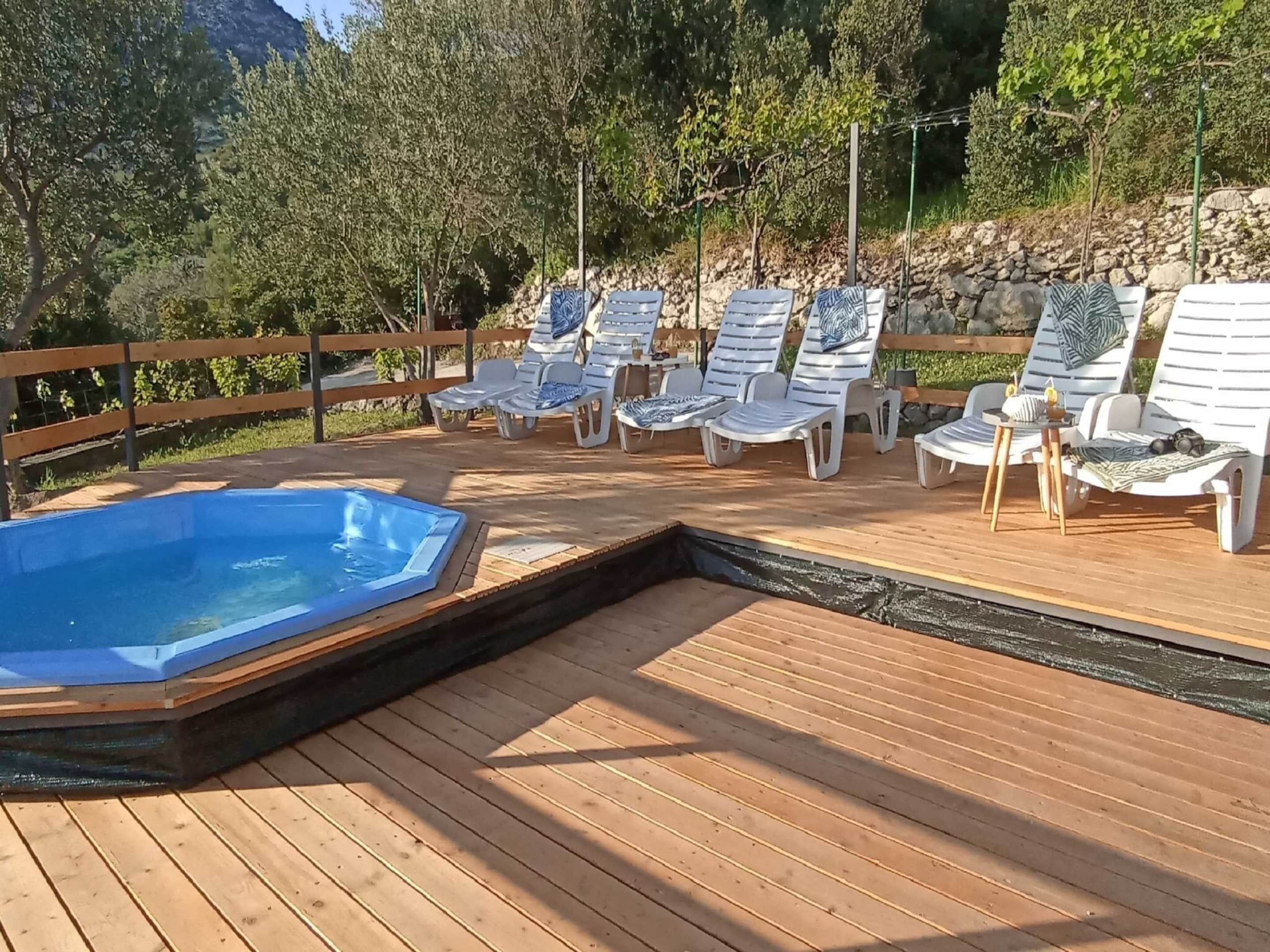 A wooden deck with lounge chairs and a hot tub.