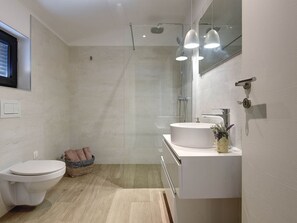 A modern bathroom with a toilet, sink, and shower.