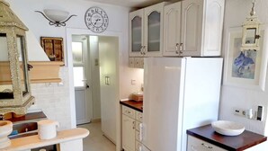 Una cocina con armarios blancos, un refrigerador, un reloj y una ventana.