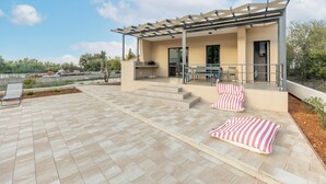 A modern outdoor patio with a pergola, a barbecue area, and a seating arrangement with cushions. - Holiday Home in Bilice With Pool (Bilice)