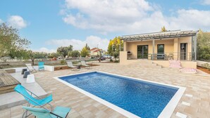 A swimming pool with lounge chairs and a covered seating area. - Holiday Home in Bilice With Pool (Bilice)
