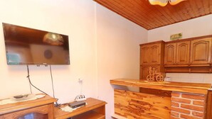 A kitchen with wooden cabinets, a TV mounted on the wall, and a counter with a brick design. - Apartments Peselj-one Bedroom Apartment With Balcony and Sea View (Smokvica)