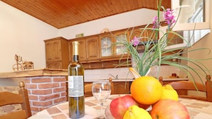 A dining table with a bottle of wine, a glass, and a bowl of fruit. - Apartments Peselj-one Bedroom Apartment With Balcony and Sea View (Smokvica)