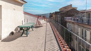 A rooftop terrace with a green table, a red swing, and a view of the cityscape.