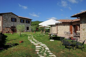 A stone building with a patio area, outdoor seating, and a stone pathway. - Farmhouse Passignano Near Lake Trasimeno (Passignano sul Trasimeno)