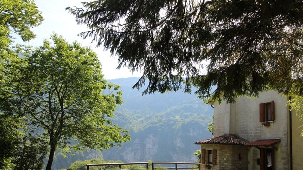 A rustic stone building with a tiled roof, a wooden bench, and a picnic table in a lush green setting with trees and a mountain backdrop. - Holiday Home in Cison With Mountain Views (Cison di Valmarino)