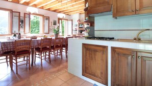A spacious kitchen with wooden cabinets, a large island, and a dining area with chairs and a table. - Holiday Home in Cison With Mountain Views (Cison di Valmarino)