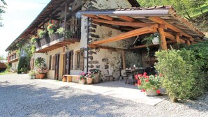 A rustic chalet with a stone facade, wooden balconies, and potted plants. - Holiday Home in Feltre With Garden BBQ (Pedavena)