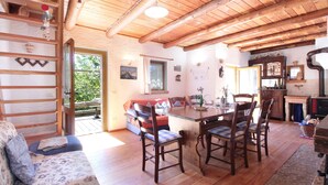 A cozy room with a wooden ceiling, a dining table with chairs, a sofa, and a fireplace. - Alpine Getaway for Families (Lamon)