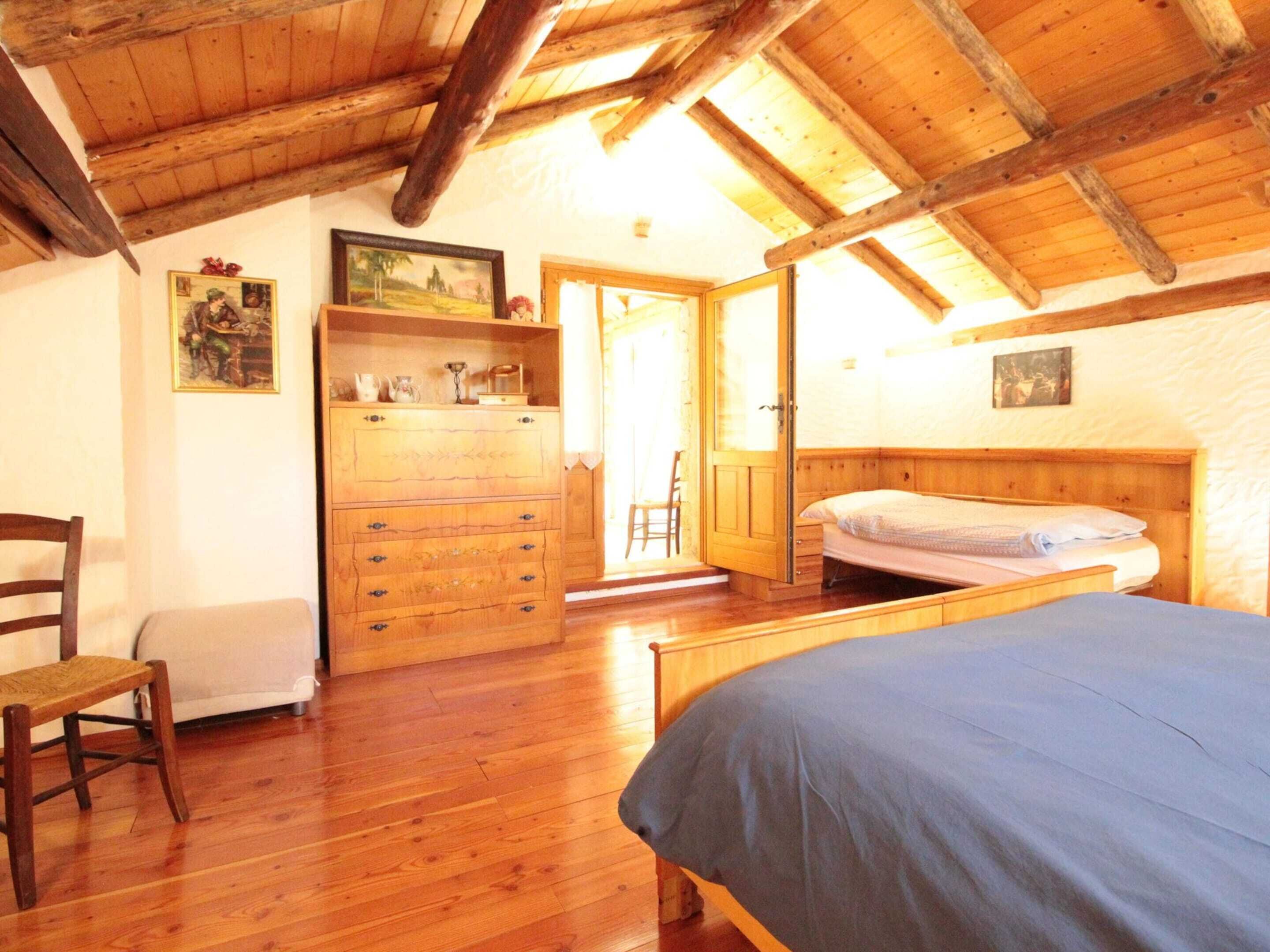 Una habitación con estructura de madera, una cama, un aparador y una silla.
