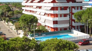 Un hotel de varios pisos con piscina, balcones y techo ajardinado.