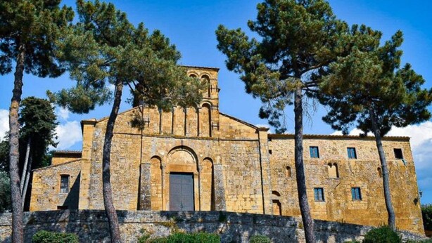 A historic stone building with a central arched entrance and multiple windows, surrounded by tall trees. - Villa in Tuscany With Pool and Hot Tub (Gambassi Terme)