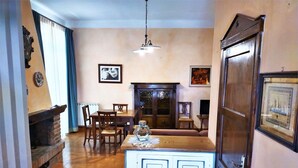 A dining area with a wooden table and chairs, a fireplace, and a large cabinet with doors. - Villa in Tuscany With Pool and Hot Tub (Gambassi Terme)