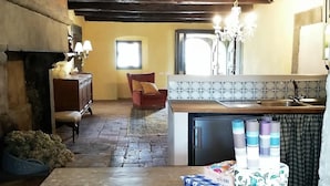 A cozy kitchen with a tiled backsplash, a wooden ceiling, and a small dining area with a chair and table. - Independent Apartment With Pool (San Godenzo)