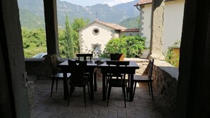 A stone patio with a table and chairs, overlooking a mountainous landscape. - Independent Apartment With Pool (San Godenzo)