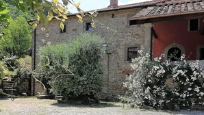 A stone building with a red facade, a chimney, and a gravel driveway. - Independent Apartment With Pool (San Godenzo)
