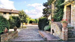 A stone pathway leading to a rustic building with a tiled roof, surrounded by greenery and potted plants. - Relaxing Stay in Gambassi Terme (Gambassi Terme)
