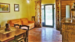 A cozy room with a wooden ceiling, a sofa, a dining table with chairs, and a door leading outside. - Relaxing Stay in Gambassi Terme (Gambassi Terme)