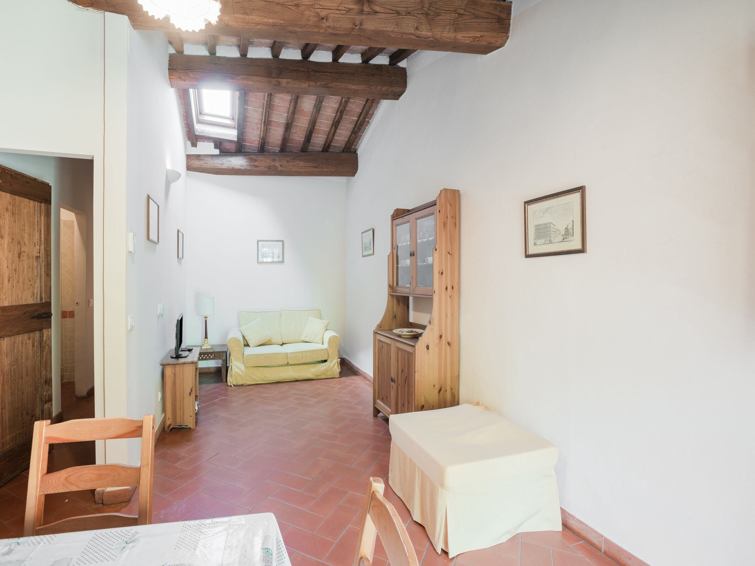 A room with a wooden ceiling, a sofa, a small table, a cabinet, and a chair.