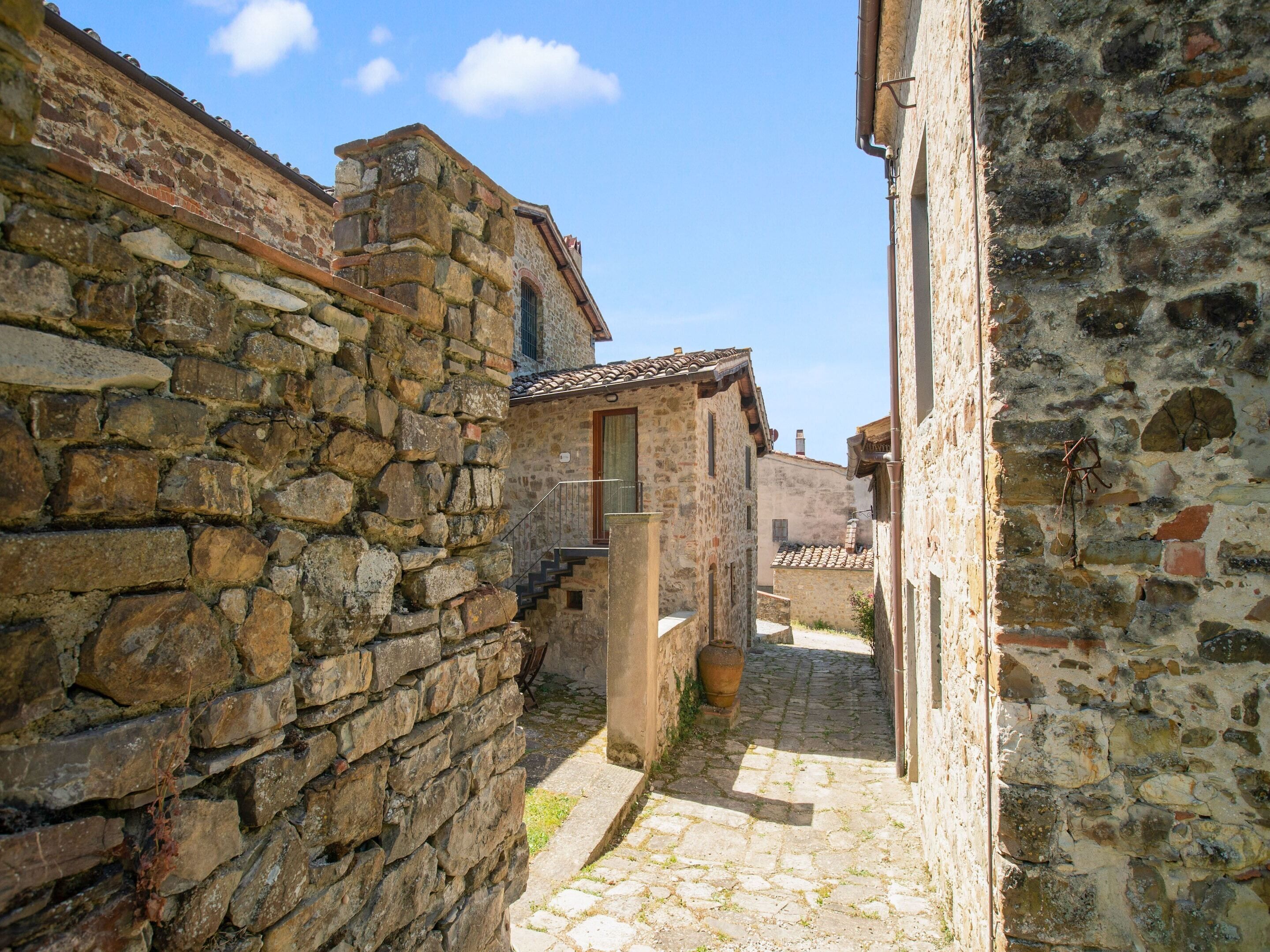 A narrow stone alleyway between buildings with a cobblestone path.
