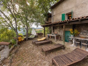 A rustic outdoor seating area with wooden furniture, a dining table, and a green door.