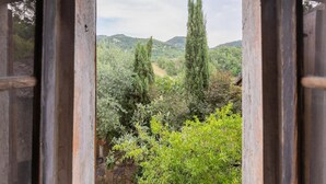 A rustic wooden door frame with a view of a lush garden and distant hills. - Belvilla by Oyo Casa Marchi (Vergato)