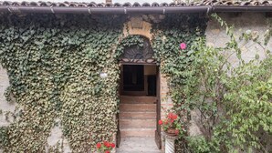 A rustic building with a covered entrance, ivy-covered walls, and a stone staircase leading inside. - Belvilla by Oyo Casa Marchi (Vergato)