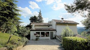 Una casa tradicional con un camino de piedra que lleva a la entrada, rodeada de vegetación y árboles.