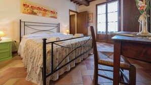 A bedroom with a bed, a desk, a chair, a window, and a door. - Belvilla by OYO Giglio (Cerreto Guidi)