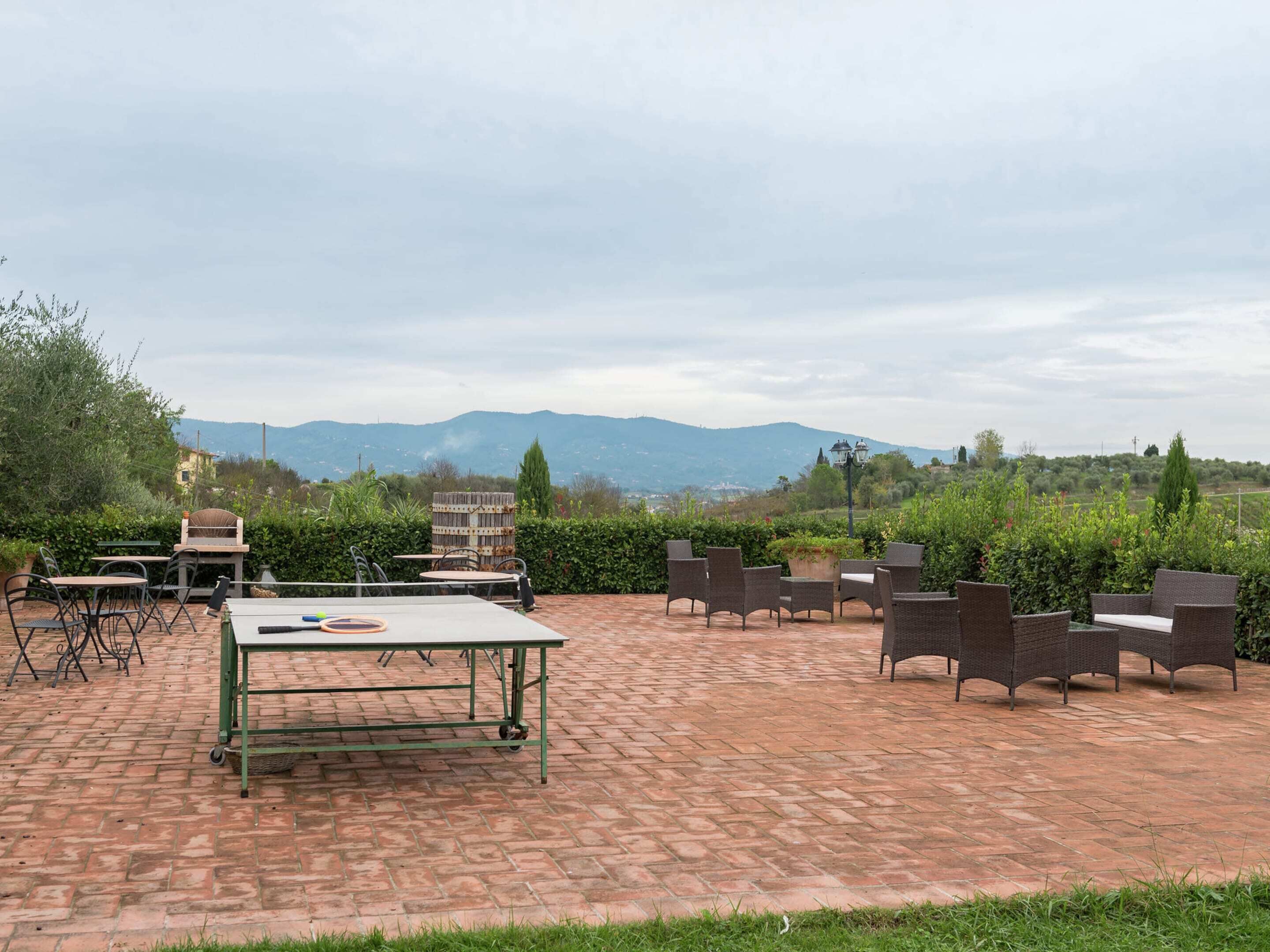 Un patio al aire libre con suelo de ladrillo, mobiliario de mimbre y una mesa.