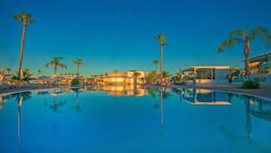 A clear blue pool with palm trees and modern buildings in the background. - Marlita Beach Hotel Apartments (Paralimni)