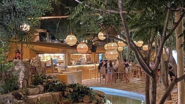 An indoor garden with a water feature, seating areas, and a bar/lounge area with hanging lights. - Marlita Beach Hotel Apartments (Paralimni)