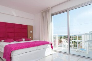 Ein modernes Hotelzimmer mit einem großen Bett, einem Balkon mit weißen Stühlen und Blick auf die Landschaft.