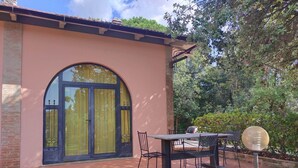 A building with a large arched window, a brick exterior, and a patio area with a table and chairs. - Tuscany Escape With Pool (Gambassi Terme)