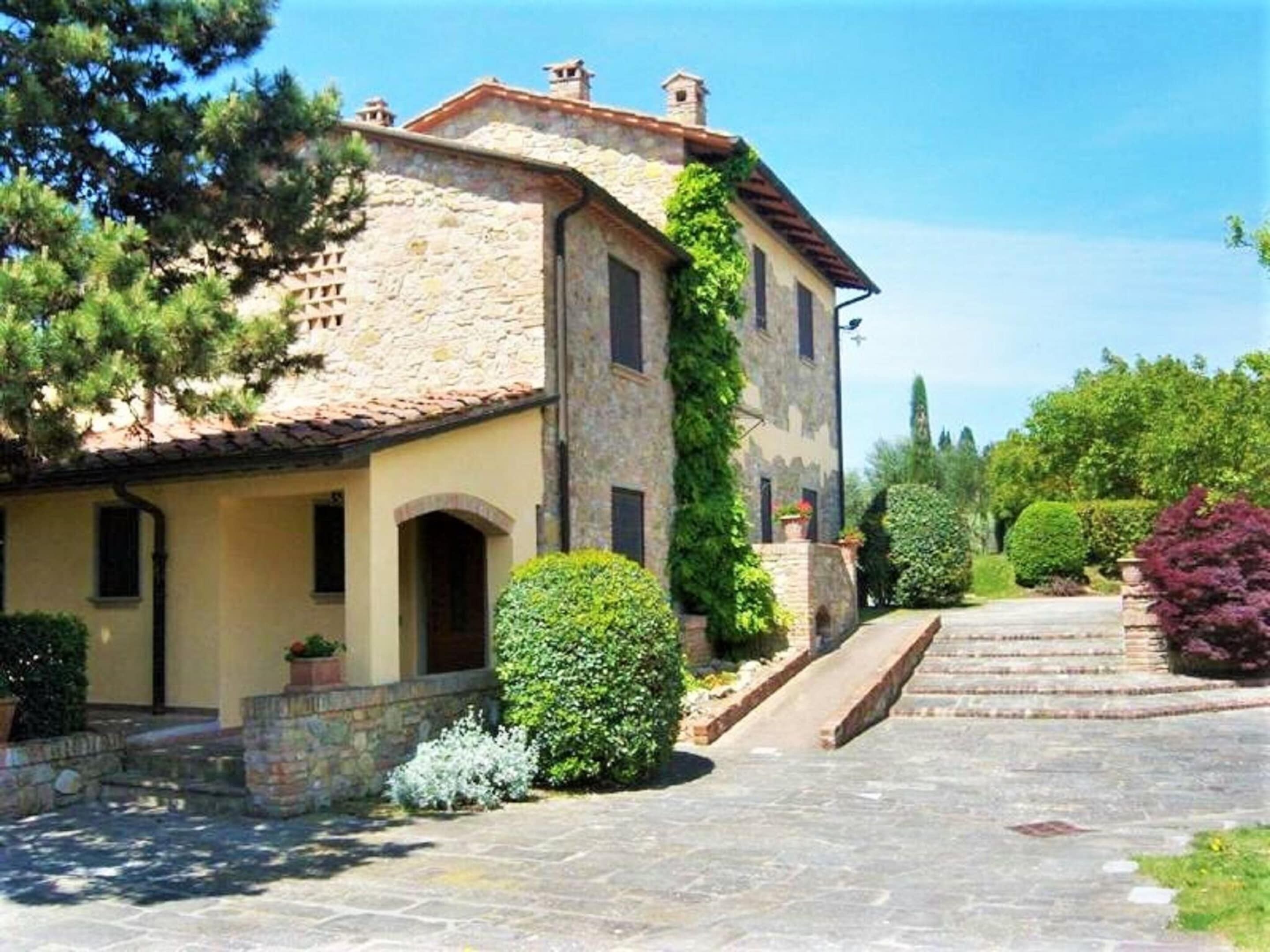 A stone building with a tiled roof, a covered porch, and a stone staircase leading to the entrance.