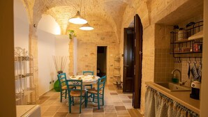 A rustic kitchen with exposed stone walls, a round table with chairs, and a built-in sink. - Huge Villa With Private Pool in Salento, Italy (Ceglie Messapica)