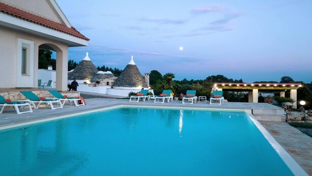 A swimming pool with lounge chairs and stone structures in the background. - Huge Villa With Private Pool in Salento, Italy (Ceglie Messapica)